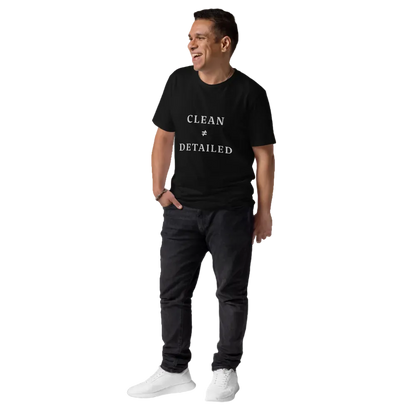 Man wearing a black t-shirt with 'Clean & Detailed' text, dark pants, and white shoes on a white background